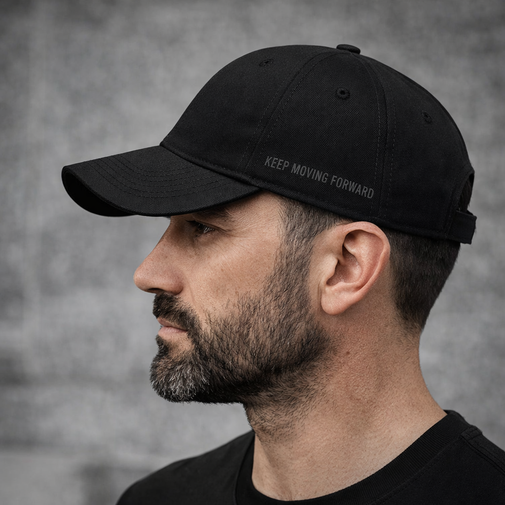 Man wearing a Krav Maga black cap with 'KEEP MOVING FORWARD' text against a gray background